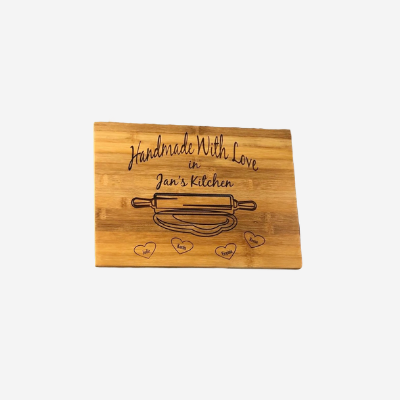 bamboo cutting board engraved "Handmade with Love in Jan's Kitchen" with rolling pin, dough, and grandkids names