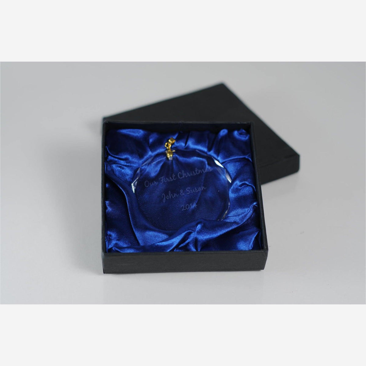circle crystal ornament with gold clasp engraved "Our First Christmas John & Susan 2014" in black box with blue silk