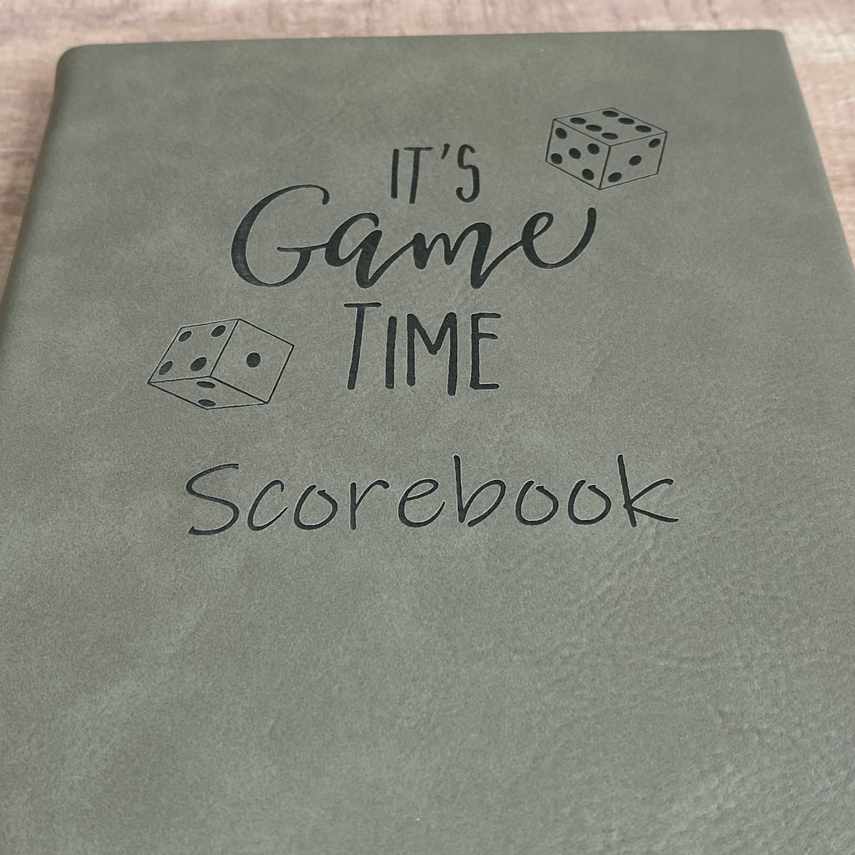 close up of gray scorepad notebook engraved with It's Game Time