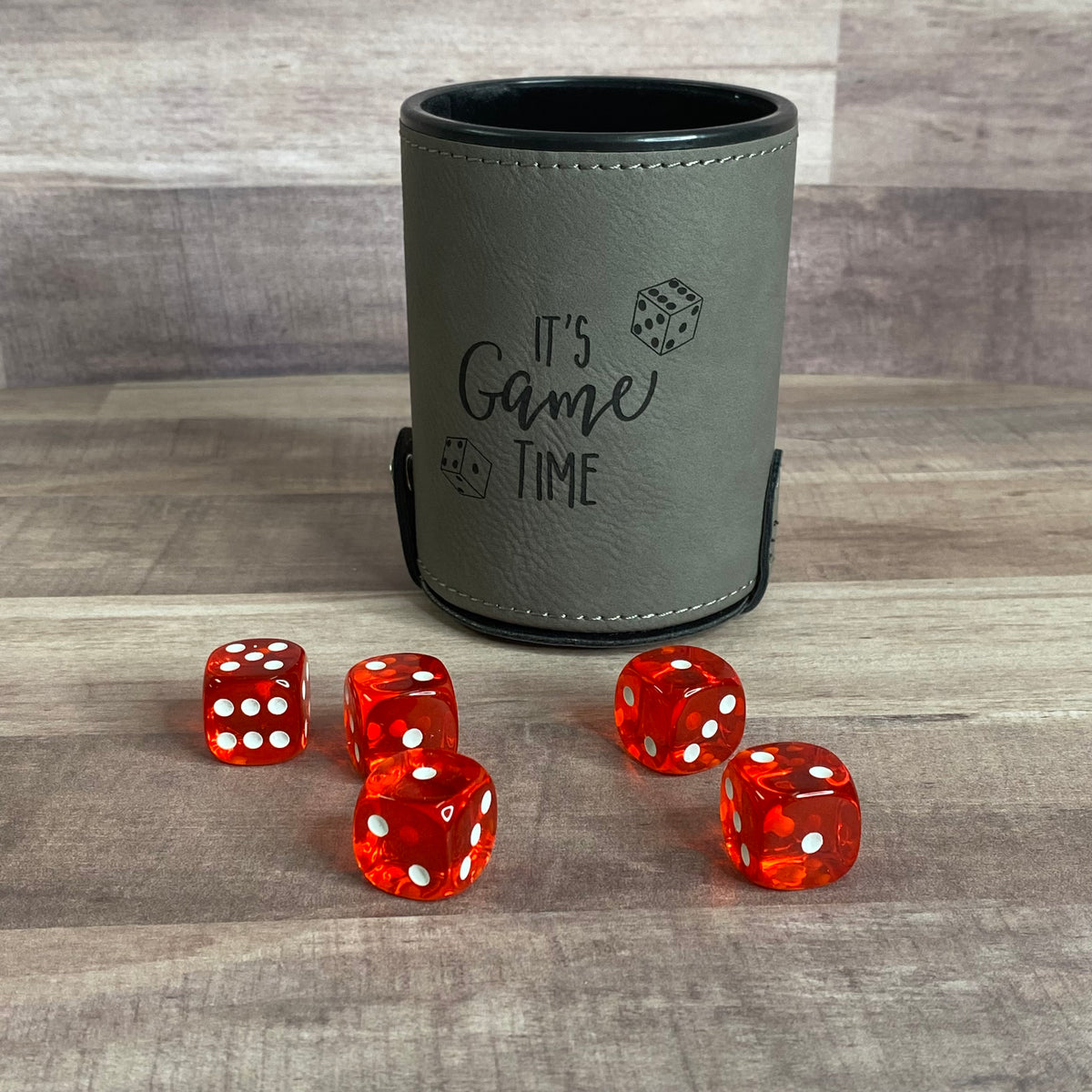 gray dice cup with red dice on table